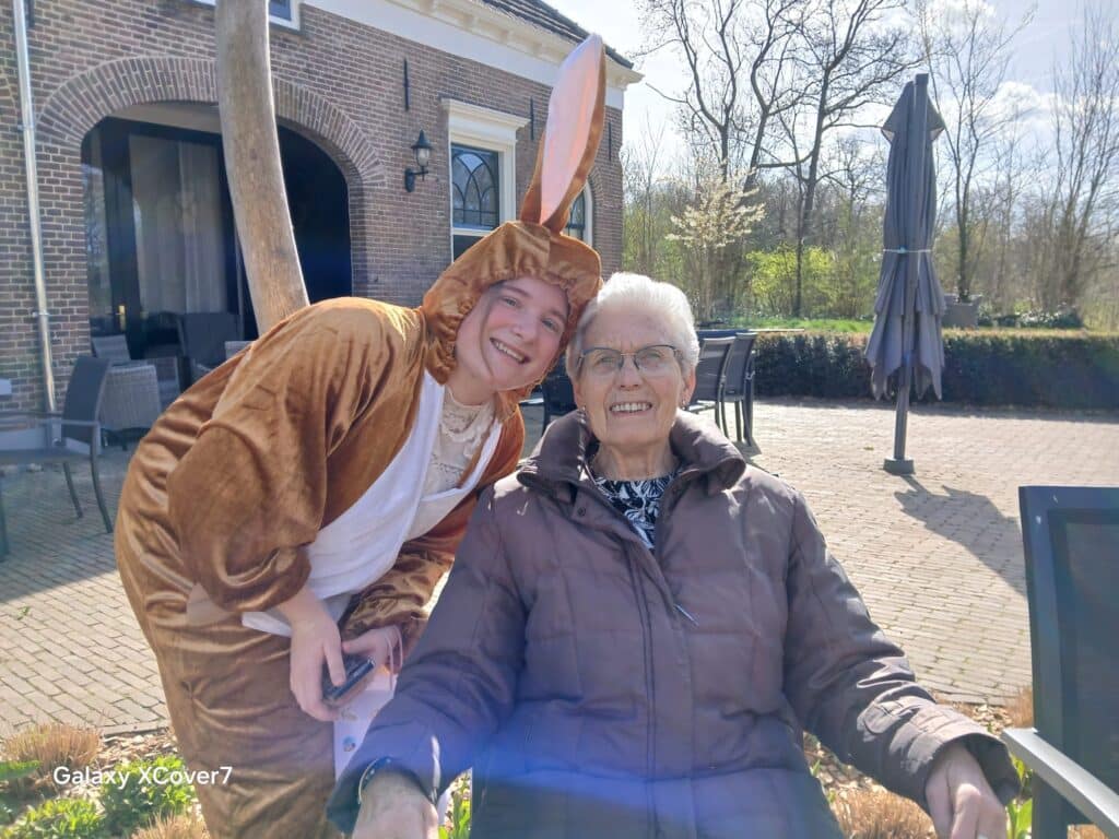 De stagiaire als paashaas samen met een bewoner buiten in de tuin van Villa Hunderen in Twello